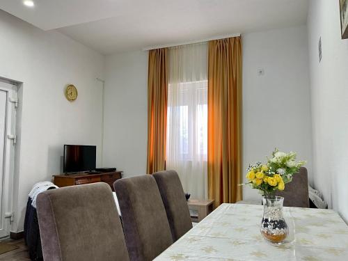 a room with a table with chairs and a vase of flowers at Apartment Jovana in Herceg-Novi