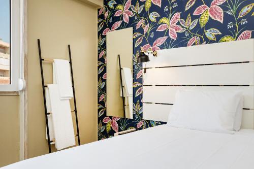 - une chambre avec un lit blanc et un papier peint floral dans l'établissement Wallis Rato, à Lisbonne