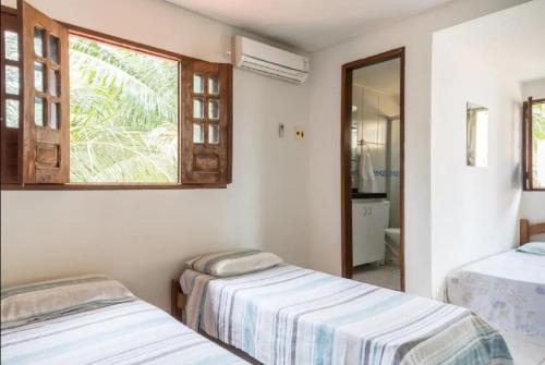 Duas camas num quarto com uma janela em Mar e Sol em Porto de Galinhas