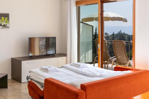 Schlafzimmer mit einem Bett, einem TV und einem Balkon in der Unterkunft Residence La Corte Danese in Torri del Benaco