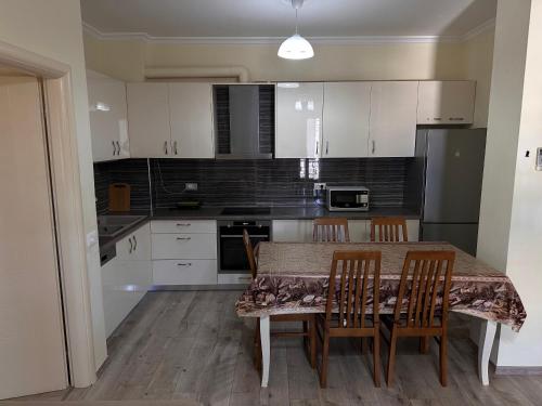 eine Küche mit weißen Schränken sowie einem Tisch und Stühlen in der Unterkunft Family Apartaments in Sarandë