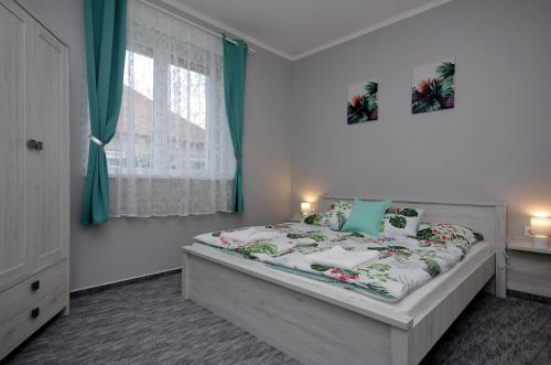 a bedroom with a bed with green and white sheets at Happy Moments Apartman in Gyula