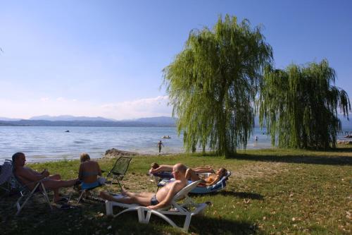 a group of people sitting on lawn chairs on the beach at San Francesco Camping Village in Desenzano del Garda