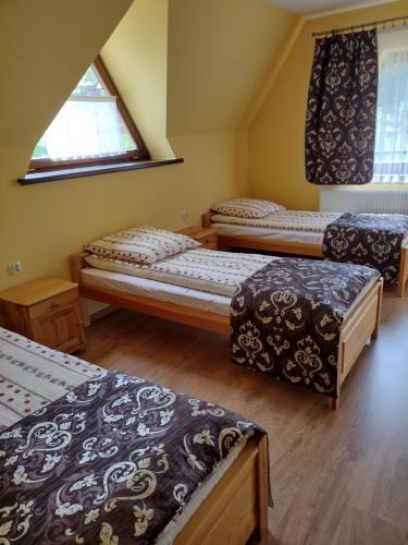 LeśnicaにあるPokoje Gościnne U Teresyのベッド3台と窓が備わる客室です。