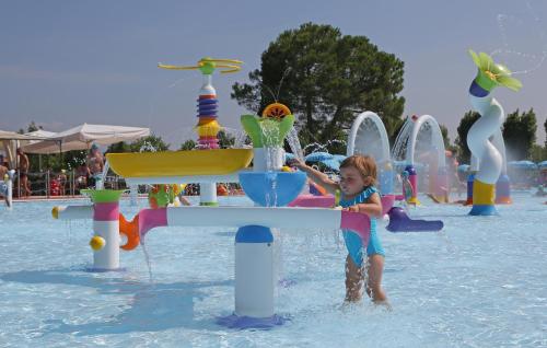 a little girl playing in the water at a water park at San Francesco Camping Village in Desenzano del Garda