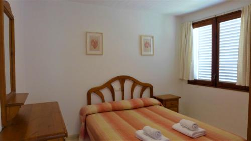 a bedroom with a bed and a table and a window at Apartamentos Colon in Salou