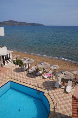 ein Swimmingpool neben einem Strand mit Sonnenschirmen in der Unterkunft Cozy Corner VS Beachfront in Stalós