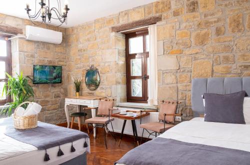 a bedroom with two beds and a table and a desk at Salkım Otel Gökçeada in Gokceada Town