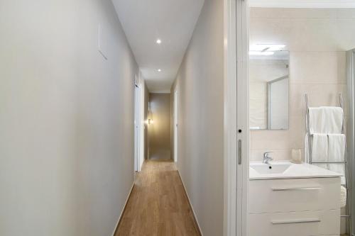 La salle de bains blanche est pourvue d'un lavabo et d'un miroir. dans l'établissement A Casa da Elsa, à Faro