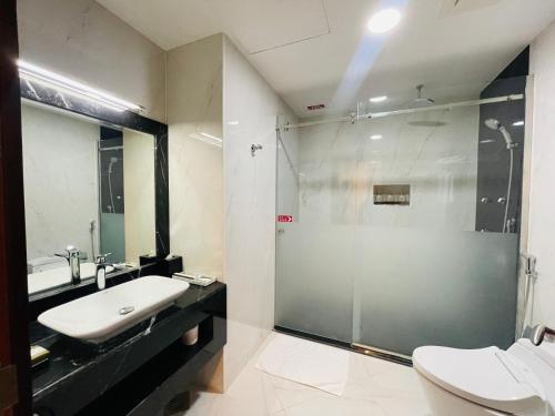 a bathroom with a glass shower and a sink at Grand Legacy Hotel Doha in Doha