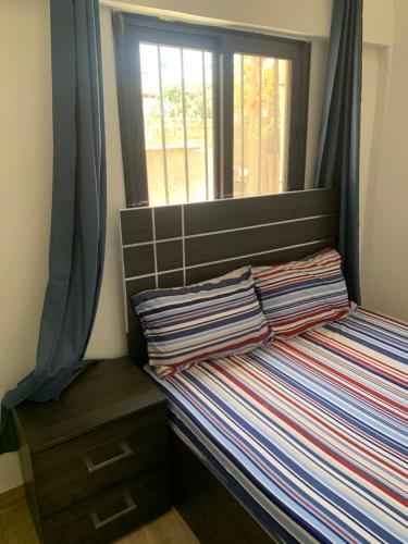 a small bedroom with a bed with a window at residence hadja Mamelles in Dakar