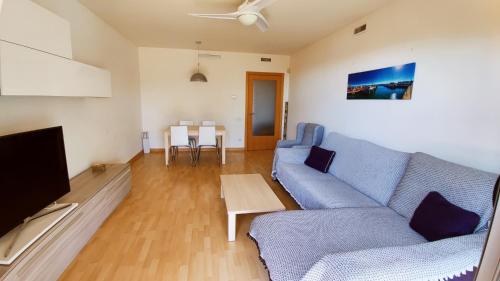 Mirador del Delta في Camarles: غرفة معيشة مع أريكة زرقاء وتلفزيون