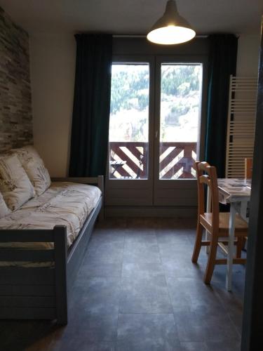 une chambre avec un lit, une table et une fenêtre dans l'établissement Agréable appartement proche Funiculaire, à Bourg-Saint-Maurice