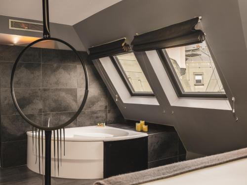 a bathroom with a bath tub and a window at Legend Hôtel Paris in Paris