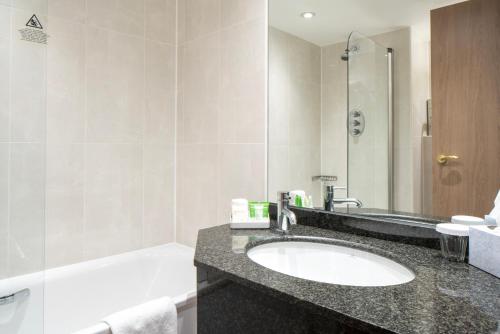 a bathroom with a sink and a bath tub at Danubius Hotel Regents Park in London