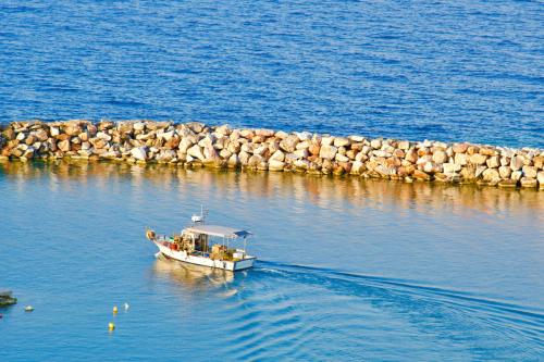 a small boat in the water next to a rock wall at Sevasti Rafina in Rafina