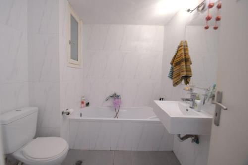 a white bathroom with a toilet and a sink at Sevasti Rafina in Rafina