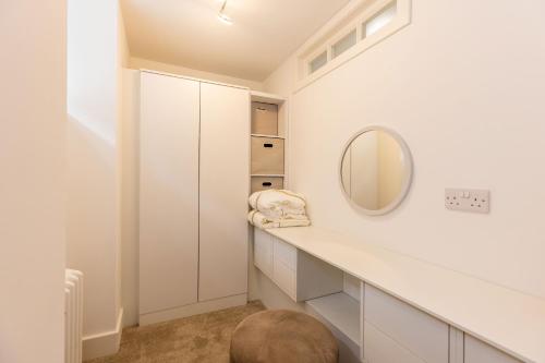 baño con armarios blancos y espejo en RÌGH Properties - Luxury West End Artisan Apartment en Edimburgo