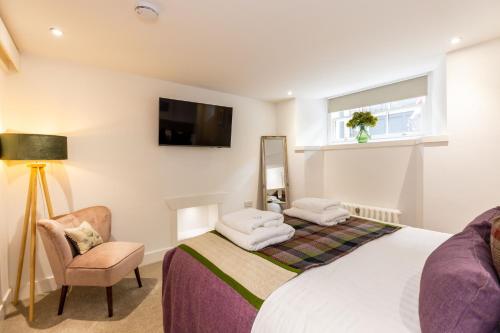 een slaapkamer met een bed en een stoel en een tv bij RÌGH Properties - Luxury West End Artisan Apartment in Edinburgh