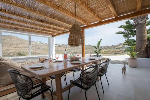 a dining room with a wooden table and chairs at Levantes House Mykonos in Ano Mera