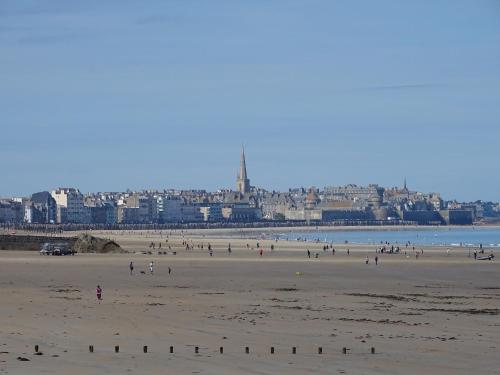 un groupe de personnes sur une plage avec une ville en arrière-plan dans l'établissement Appartement Philomène, à Saint-Malo