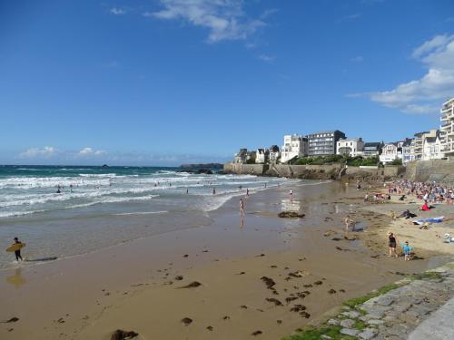 un groupe de personnes sur une plage avec l'océan dans l'établissement Appartement Philomène, à Saint-Malo