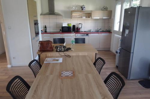 a kitchen with a wooden table with chairs and a refrigerator at Spacious and cosy 80 m house located in Séné in Séné