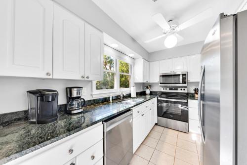a kitchen with white cabinets and a stainless steel refrigerator at 507 Tarpon Pond Cottage in Johns Island