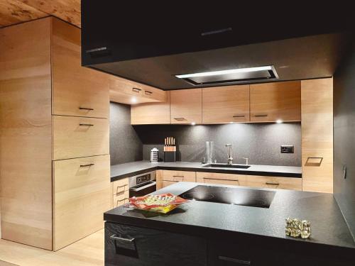 eine Küche mit Holzschränken und einer schwarzen Arbeitsplatte in der Unterkunft Reseda 222 in Crans-Montana