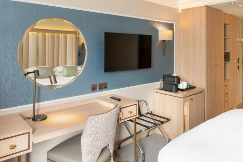 a hotel room with a desk and a mirror at Danubius Hotel Regents Park in London