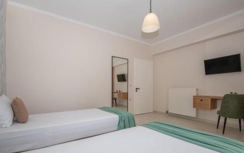 a white bedroom with two beds and a desk at Kozanos Hotel & Suites in Amoudi