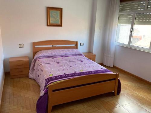 a bedroom with a wooden bed with a purple comforter at Piso lola 2 in Camariñas