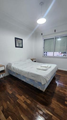 ein Schlafzimmer mit einem Bett in einem Zimmer mit Holzböden in der Unterkunft Departamento Shoping Alto Noa in Salta
