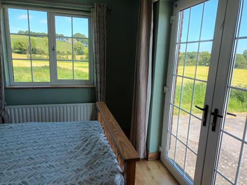 a bedroom with a bed and windows with a view of a field at Rathgillen Mews in Nobber