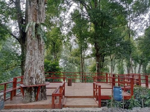 a wooden deck with a tree and a red fence at Mala Green Camp in Pengalengan