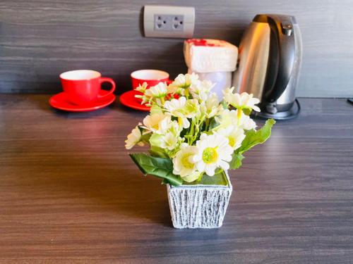 a vase of flowers on a counter with two cups at Edge Central Pattaya Vip Condo in Pattaya Central