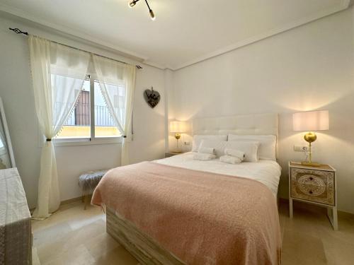 a white bedroom with a large bed and a window at Casa Playa de Garrucha in Garrucha
