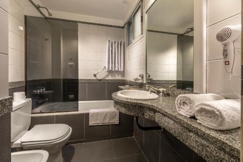 a bathroom with a toilet and a sink and a mirror at Gran Hotel Argentino in Buenos Aires