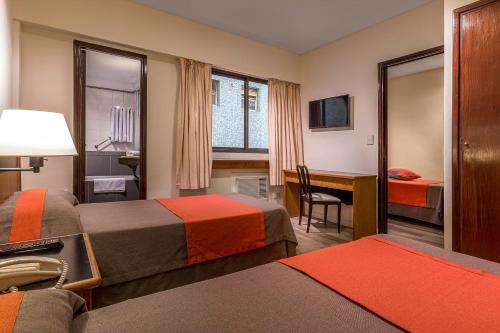 a hotel room with two beds and a desk at Gran Hotel Argentino in Buenos Aires