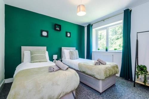 two beds in a room with a green wall at Penny Bridge Home From Home in Saint Helens