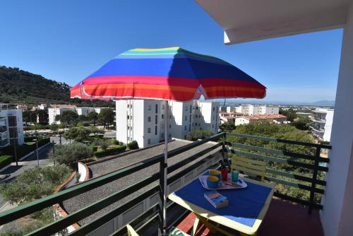 Una mesa con una sombrilla de colores en un balcón. en RNET - Mas Oliva Studio, piscina, terraza, en Roses