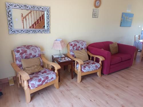 a living room with two chairs and a red couch at Rathgillen Mews in Nobber