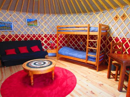 Saint-Georges-des-HurtièresにあるNuit insolite en Yourteのベッド、ソファ、テーブルが備わる客室です。