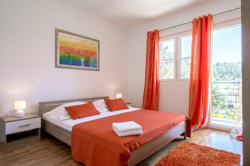 1 dormitorio con cama con sábanas de color naranja y ventana en Apartments Triporte, en Vela Luka