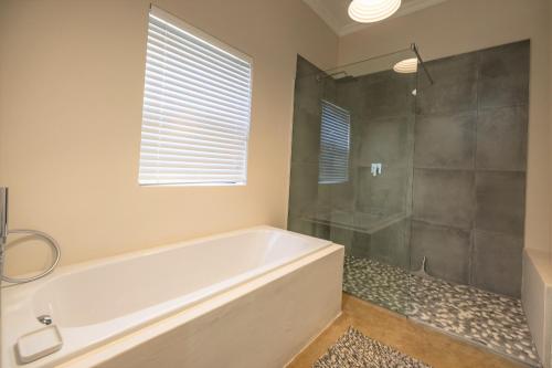 a bathroom with a tub and a glass shower at Fairfax Cottage in Nottingham Road