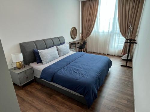 a bedroom with a large bed with a blue blanket at Home Abroad 1 Jazz Suites Vivacity in Kuching