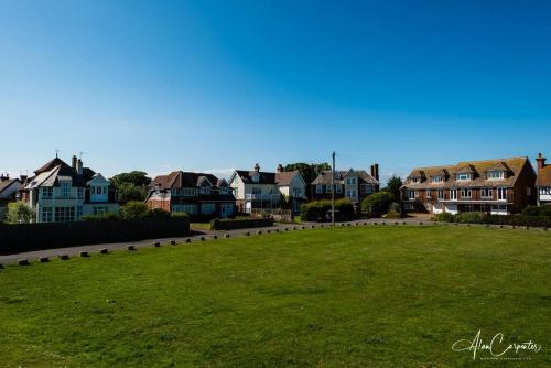 un campo de hierba con casas en el fondo en Beachside period family home. 5 BR spacious, comfortable., en Dymchurch