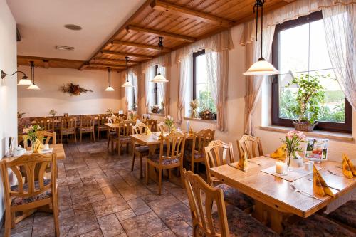 a restaurant with wooden tables and chairs and windows at Hotel Waldesruh in Lengefeld