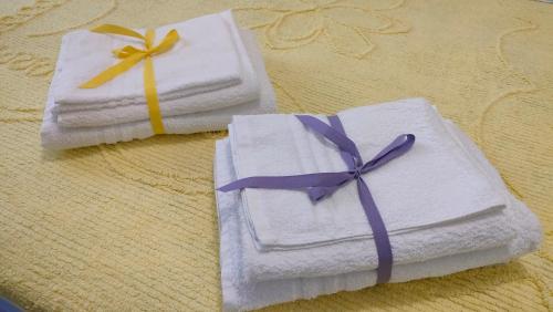 due asciugamani bianchi con fiocchi viola su un tavolo di La Casetta a Montesilvano