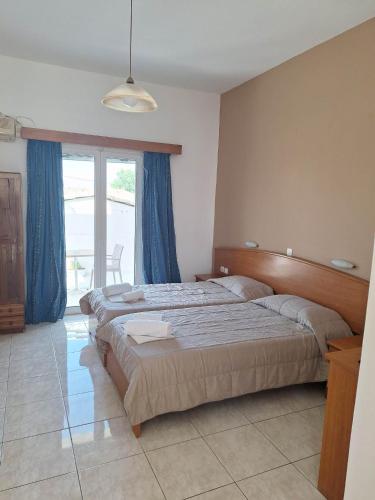 a bedroom with two beds and a large window at Two Brothers Studios Tsilivi Zakynthos in Tsilivi